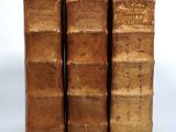 three old books are stacked on top of each other on a white surface