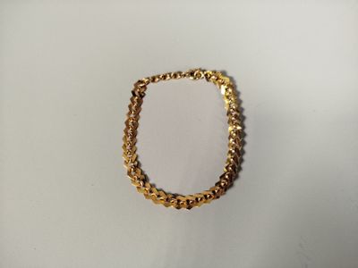 a close up of a gold chain bracelet on a white surface