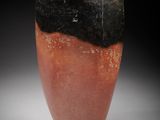 an orange and black vase sitting on top of a white table