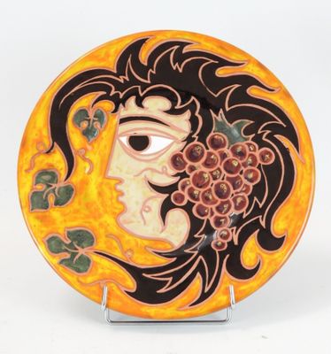 assiette jaune et noire ornée d'un visage de femme et de raisins