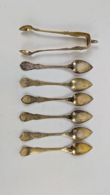 six cuillères et un repose-cuillère sur une surface blanche