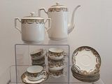 une étagère en verre sur laquelle sont posés une théière, des tasses et des soucoupes