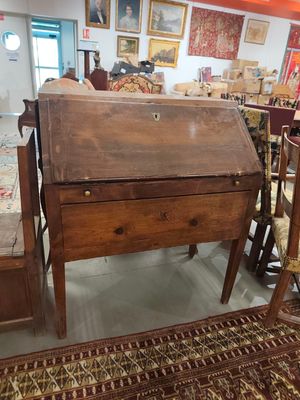 un bureau et une chaise en bois dans une pièce où sont accrochés des tableaux au mur