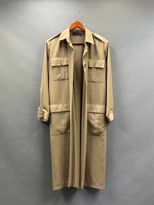 un manteau beige suspendu à un cintre devant un mur gris