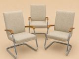 trois chaises avec accoudoirs sur fond beige, avec un fond beige