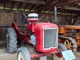 un tracteur rouge dans une grange, avec une pancarte à l'avant