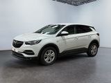 Une voiture blanche est garée dans une pièce blanche au sol noir.