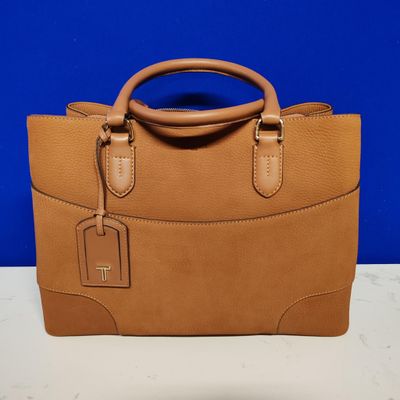 a brown handbag sitting on top of a table next to a blue wall