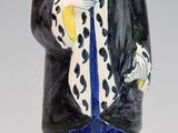 une figurine représentant un homme vêtu d'un manteau et d'un chapeau