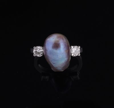 an oval pearl and diamond ring on a black surface