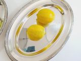 two lemons sitting on a silver tray with a mirror