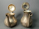 two silver vases sitting next to each other on a table