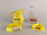 a yellow pitcher next to a glass bottle and a yellow ashtray