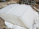 a pile of mattresses on the ground in front of a fence