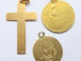 two gold crosses and a gold medal on a white surface