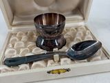 a silver cup and spoon in a box with a spoon and spoon rest