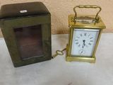 a small clock sitting next to a box on a table