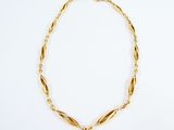 a gold necklace with a twisted link and a clasp