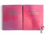two pink books are open on a white surface with a red cover