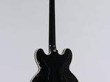 a black electric guitar hanging from a white wall