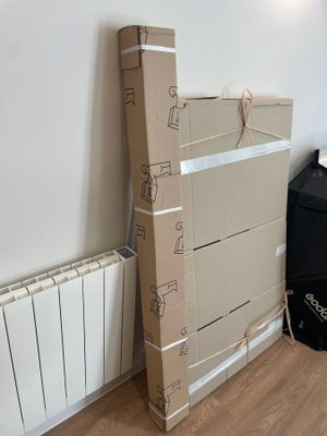 une pile de cartons posée par terre à côté d'un radiateur