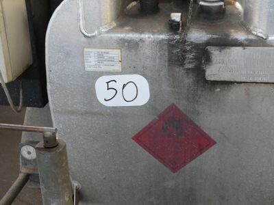 a metal tank with a red and white sign on it
