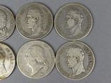 six different types of silver coins are shown on a gray surface