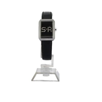 une montre noire et argentée posée sur un socle, sur fond blanc