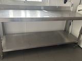 une table en acier inoxydable dans une cuisine équipée d'un lave-linge