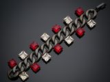 a close up of a metal bracelet with red and white stones