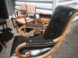 a black leather chair with a wooden seat and foot rest