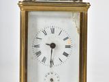 a small gold clock with roman numerals on the face