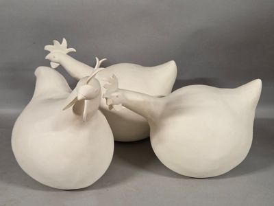 three white vases sitting on a table with one of them holding a bird