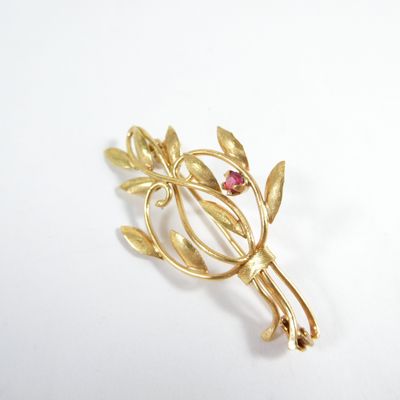 une broche en or ornée de feuilles et d'une pierre rouge