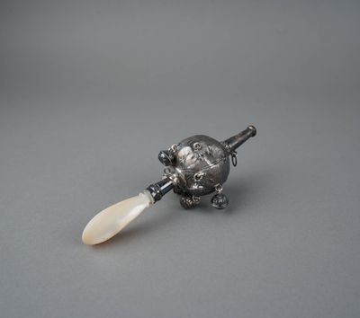 une figurine en argent représentant une tortue tenant une pagaie, posée sur un fond gris