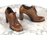 une paire de chaussures en cuir marron posée sur une table en marbre, sur fond blanc