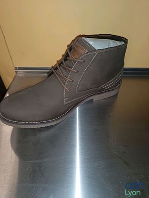 des bottes grises posées sur une surface métallique, avec un mur jaune en arrière-plan