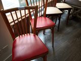 four wooden chairs sitting in a row in front of a window