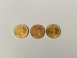 trois types différents de pièces d'or sur une surface blanche