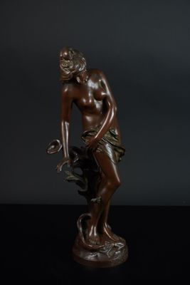 une statue en bronze d'une femme assise sur un rocher