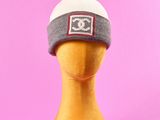 un bonnet gris et blanc sur une tête de mannequin, sur fond rose
