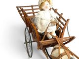 a small doll sitting in a wooden carriage with a dog