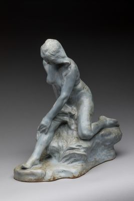 l'image d'une statue de femme assise sur un rocher