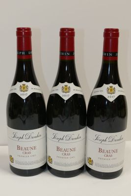 trois bouteilles de vin rouge sont alignées sur une surface blanche