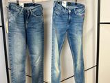 deux paires de jeans suspendues à un portant dans un magasin de vêtements