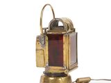 an antique brass and red glass lamp on a white surface
