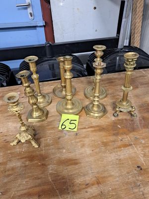 cinq bougeoirs en laiton posés sur une table, accompagnés d'une étiquette de prix