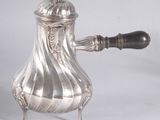 a silver coffee pot on a stand with a wooden handle