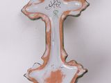 a ceramic cross hanging on a wall on a white background