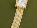 an image of a gold watch with a white face on a green surface